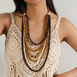 Détail d'un collier bohème multicouche avec perles en bois naturel sur gilet au crochet