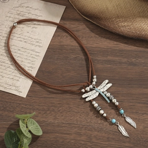 Detailed shot of bohemian dragonfly pendant with turquoise beads and silver feathers on wood