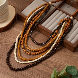 Détail d'un collier bohème multicouche avec des perles en bois sur un plateau en bois