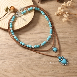 Detail van de boheemse gelaagde ketting met turquoise kralen en hartvormige hanger