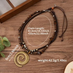 Collier bohème double couche avec pendentif spirale en laiton et perles sur fond bois
