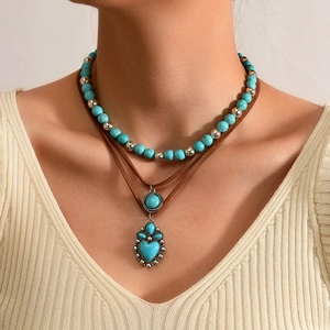 Detail van de bohemien dubbele halsketting met turquoise kralen en hart hanger