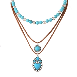Detail van boheemse gelaagde ketting met turquoise kralen en hartbedeltjes op wit