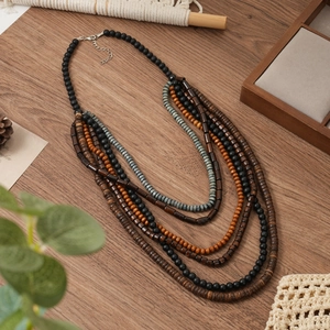 Vue détaillée du collier multicouche en perles de bois bohème sur fond de bois
