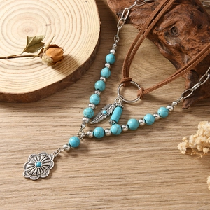 Detail van een bohemian gelaagde ketting met turquoise kralen en zilveren veerhangers