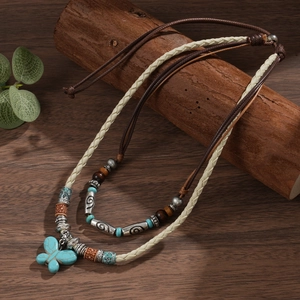 Detailed close-up of Zen style butterfly pendant and ethnic beaded necklace on dark wood