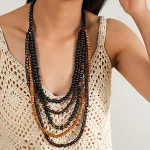 Détail d'un collier bohème multicouche avec perles en bois et œil de tigre sur modèle