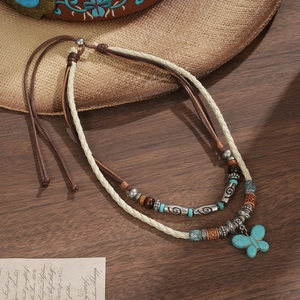 Detail view of ethnic butterfly pendant necklace with turquoise beads on wood