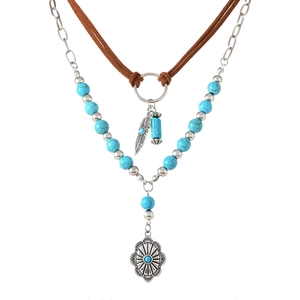 Detail van de boheemse turquoise ketting met zilveren veren- en zonvormige hangers