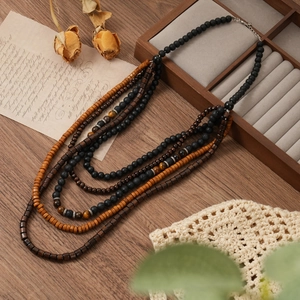 Gros plan d'un collier multicouche bohème avec perles en bois et pierres d'oeil de tigre