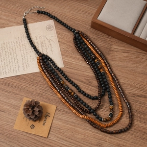 Détail d'un collier bohème multicouche avec pierre de lave, bois et œil de tigre sur bois