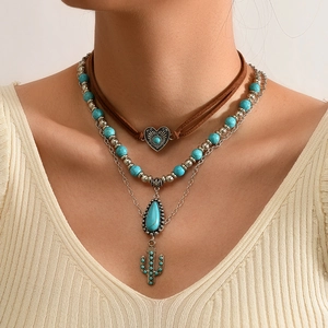 Detail van de boho gelaagde ketting met turkooizen hart, cactus en stierkop hangers