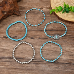 Set of 5 bohemian blue beaded bracelets with silver accents on a rustic wooden background