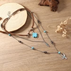 Detail van gelaagde bohemian ketting met turquoise ster, veer en cactus hangers in close-up