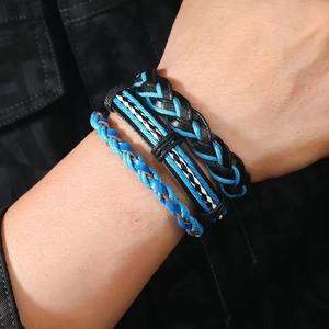 Detailed close-up of a three-piece woven bracelet set in blue and black on a male wrist