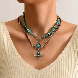 Detail van een gelaagde boho ketting met vintage stierenkop hanger en turkooissteen
