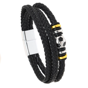 Gros plan d'un bracelet multicouche en cuir tressé avec breloque football et fermoir magnétique