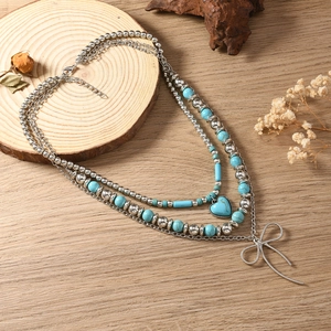 Detail van gelaagde boho-halsketting met turkoois kralen en hart- en booghanger
