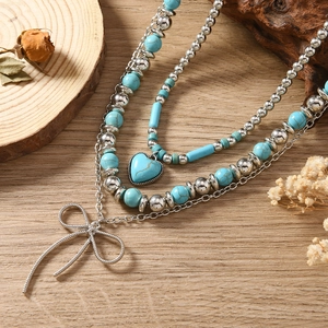 Vintage gelaagde turquoise kralenketting met hartjes hanger en strikje op hout decor