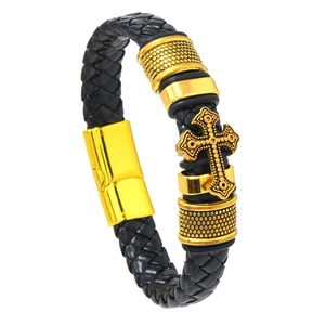 Detail of men's black braided leather bracelet featuring a golden engraved cross charm