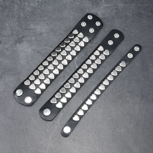 Three-piece punk black leather bracelet set with silver heart studs on rock background
