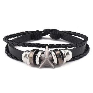 Macro detail of multilayered black leather bracelet featuring a vintage star metal charm