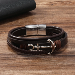 Detailed close-up of brown multilayer leather bracelet with silver anchor on wood surface