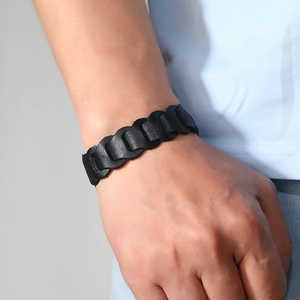 Dettaglio di un ampio bracciale in pelle nera da uomo con design a maglie a forma di U