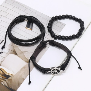 Detail view of multi-layer black leather bracelets with silver nautical helm charm