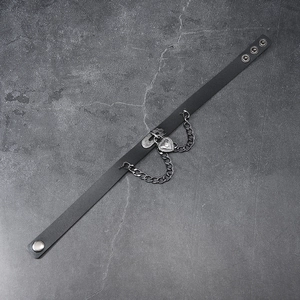 Detail of black leather punk choker with silver heart lock and metal chain on stone texture