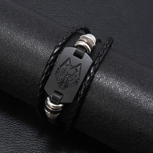 Men's braided black leather bracelet featuring a matte wolf head metal charm on a stand
