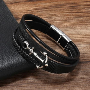 Detailed close-up of multilayer leather bracelet with a silver anchor charm on a wood surface