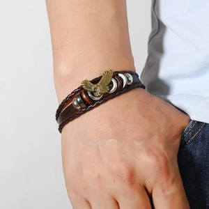 Close-up of a men's punk leather bracelet with a bronze eagle charm and woven straps