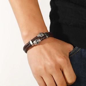 Détail du bracelet double en cuir tressé marron avec breloques crâne argentées et fermoir métal