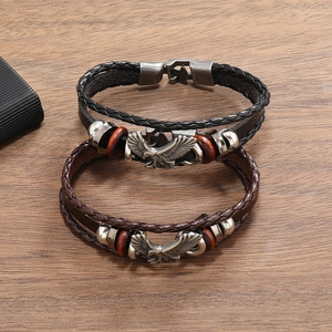 Macro shot of punk leather bracelets with eagle charms on vintage wooden background