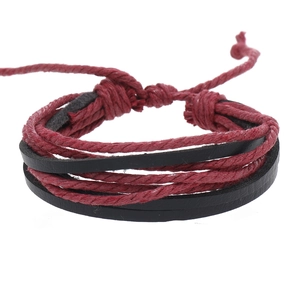 Detail of multi-layer woven bracelet featuring dark red cords and black leather bands