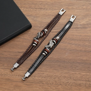 Close-up of punk braided leather bracelets with eagle charms on wood background