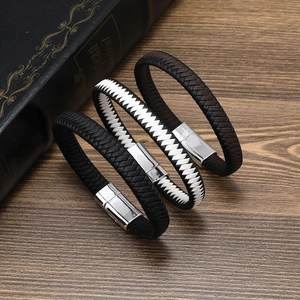 Detailed view of three braided leather bracelets with silver magnetic clasps on a vintage book