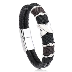 Close-up of woven leather men's bracelet with silver X-shaped metal charm and magnetic clasp