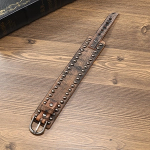 Handmade punk brown leather bracelet with metal rivets on a vintage wooden background