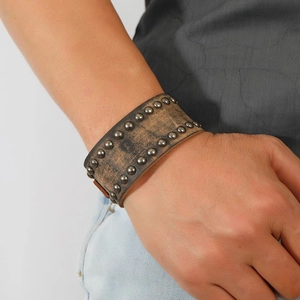 Punk style wide brown leather bracelet with vintage metal rivets on man's wrist