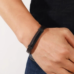Bracelet punk en cuir tressé marron foncé avec barre en métal noir poli porté au poignet