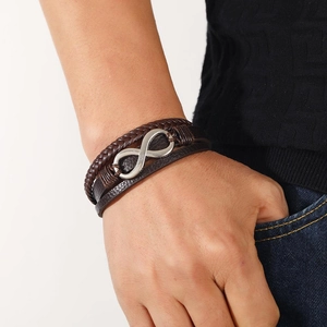 Close-up of men's brown braided leather bracelet with silver infinity symbol on wrist