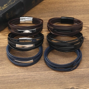 Detail of layered leather bracelets for men with magnetic clasps on a rustic wood surface