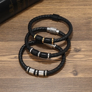 Trois bracelets en cuir tressé avec fermoirs en métal doré, argenté et noir sur bois