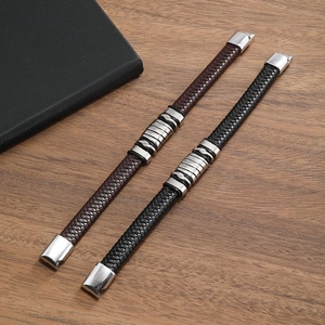 Men's woven leather bracelets in black and brown with metal rings on wooden background