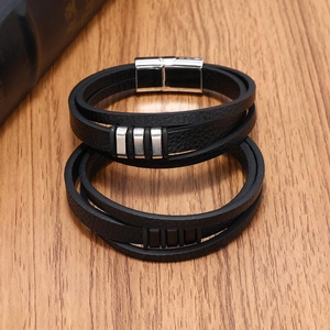 Braided black leather bracelets with polished magnetic steel clasps on a wood surface