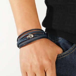 Men's multi-layer dark blue braided leather bracelet with silver skull charm on male wrist