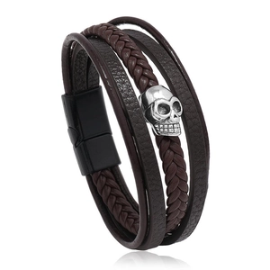 Close-up of men's multilayer braided leather bracelet with silver skull charm and magnetic clasp