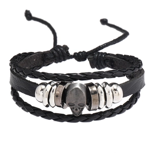 Détail d'un bracelet en cuir noir multi-rangs avec un charme tête de mort en argent vieilli